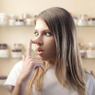 Blonde womanin white shirt making shushing gesture - revealing beauty myths