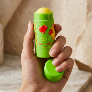 Hand holding a green Choco Smooch balm with a heart design on a neutral background