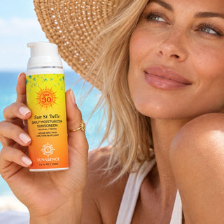 A woman in a straw hat holds a bottle of YUNASENCE Sun Si 'belle SPF 30 Daily Moisturizer Sunscreen near a beach background.