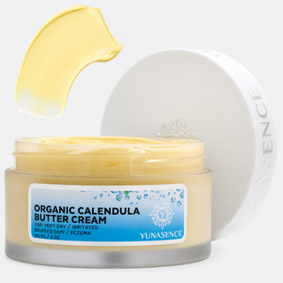 Yunaseence Organic Calendula Butter Cream in a clear jar with a white lid, showing the pale yellow cream both inside the jar and as a thick swatch above it on a white background.