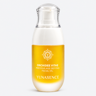 Yunasence Orchidee Vitae Precious Age Defying Facial Oil in a clear pump bottle with a white cap and a golden-yellow label, shown on a light gray background.