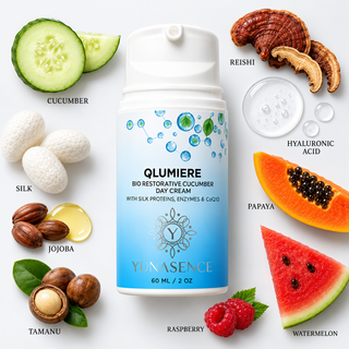 A white and blue cosmetic bottle labeled Qlumiere Bio Restorative Cucumber Day Cream is centered on a white background, surrounded by ingredient callouts including cucumber, silk, jojoba, reishi, hyaluronic acid, papaya, watermelon, raspberry, and tamanu.