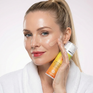 Woman applying sunscreen cream to her face with a white background