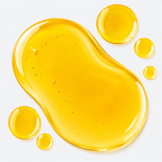 A glossy, translucent golden-yellow oil droplet with smaller droplets inside, set against a clean white background.