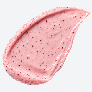 A thick, textured smear of pink cosmetic cream or scrub with small dark red berry specks, shown on a clean white background.