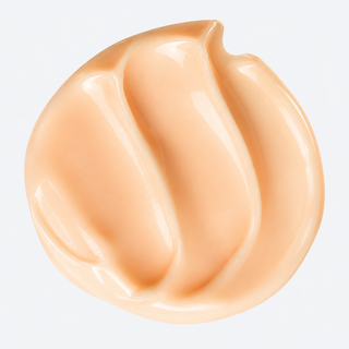 A glossy, swirled dollop of light peach-beige cosmetic cream or foundation on a clean white background.