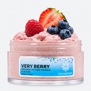 A clear plastic jar of Yunasence Very Berry Organic Oxygen Masque & Scrub, filled with pink berry-colored cream and topped with fresh berries including a sliced strawberry, a raspberry, and three blueberries, on a light gray background.
